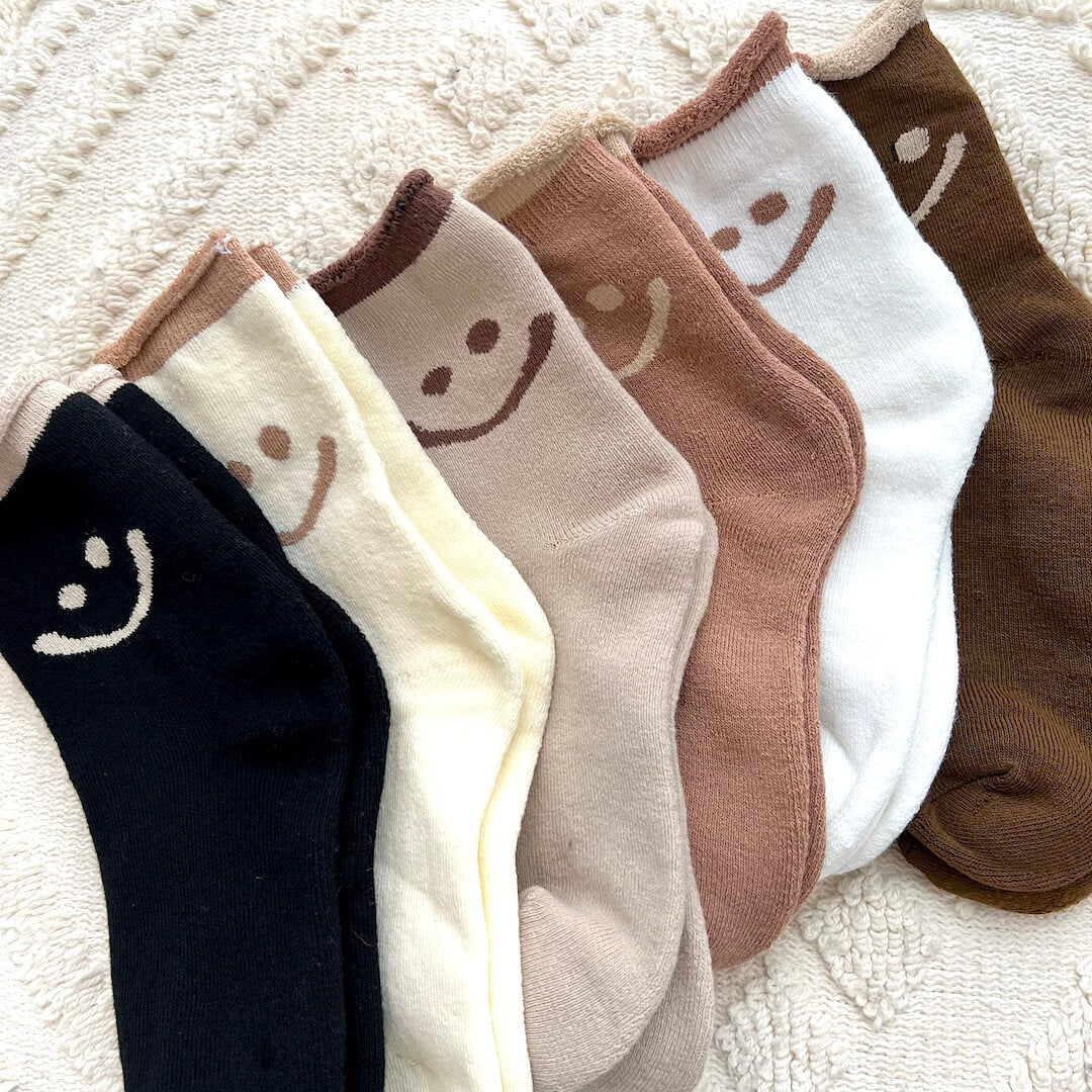 Set of socks with smiley face designs in various colors on a textured surface.