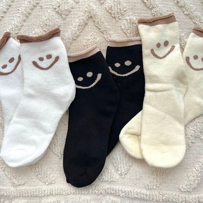 Set of socks with smiley face designs on a textured fabric background