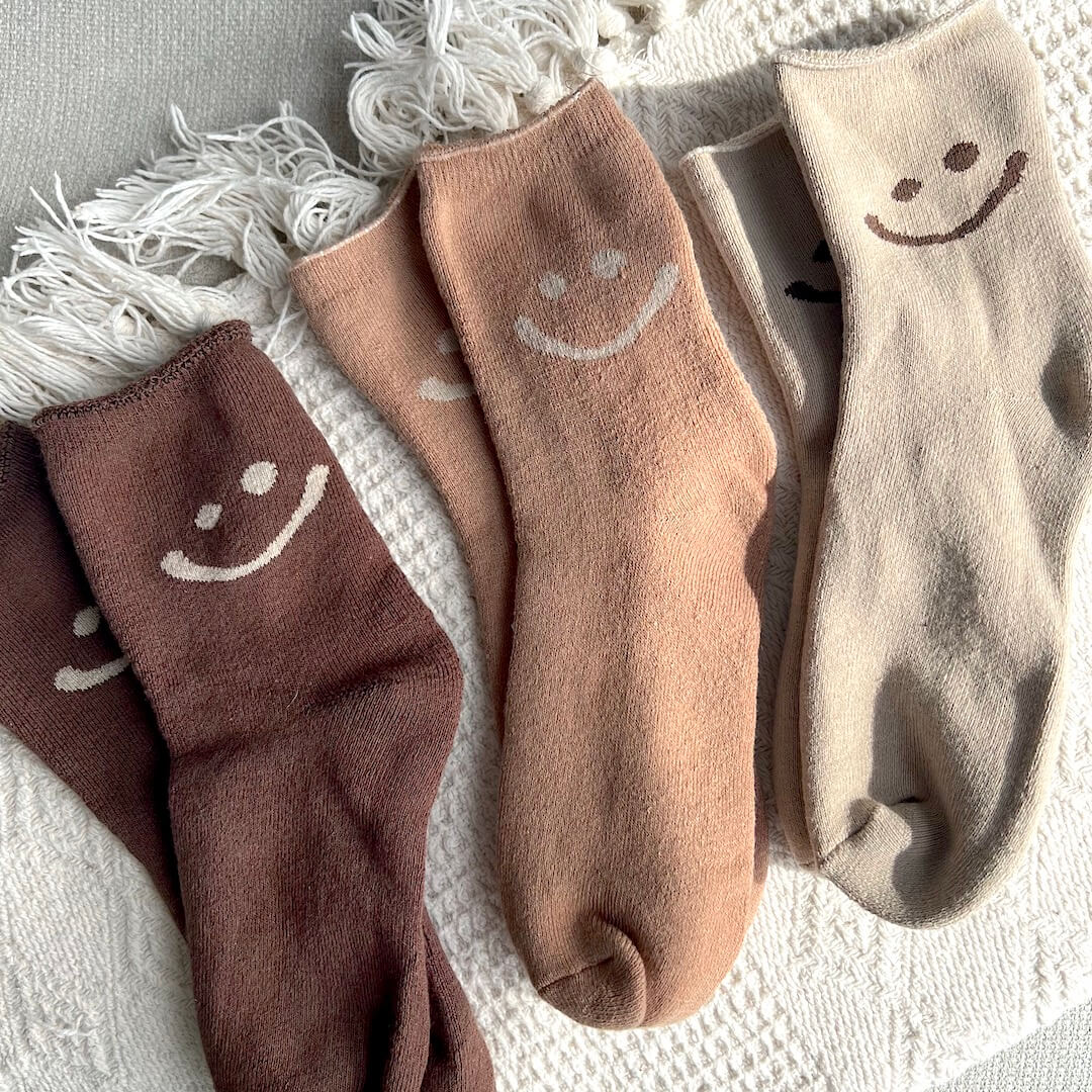 Set of four socks with smiley face designs on a textured surface