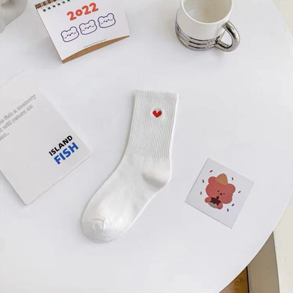 Josh & Tate - HeartStep™ Heart Crew Socks - White socks with a red heart design on a white surface with stationery items.