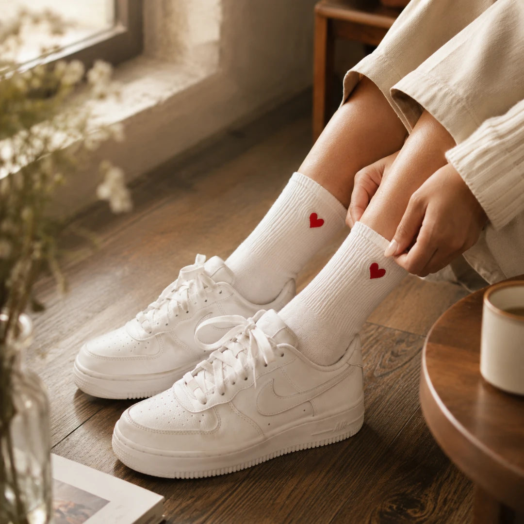 Josh & Tate - HeartStep™ Heart Crew Socks - Person wearing white sneakers and socks with red hearts on a wooden floor.