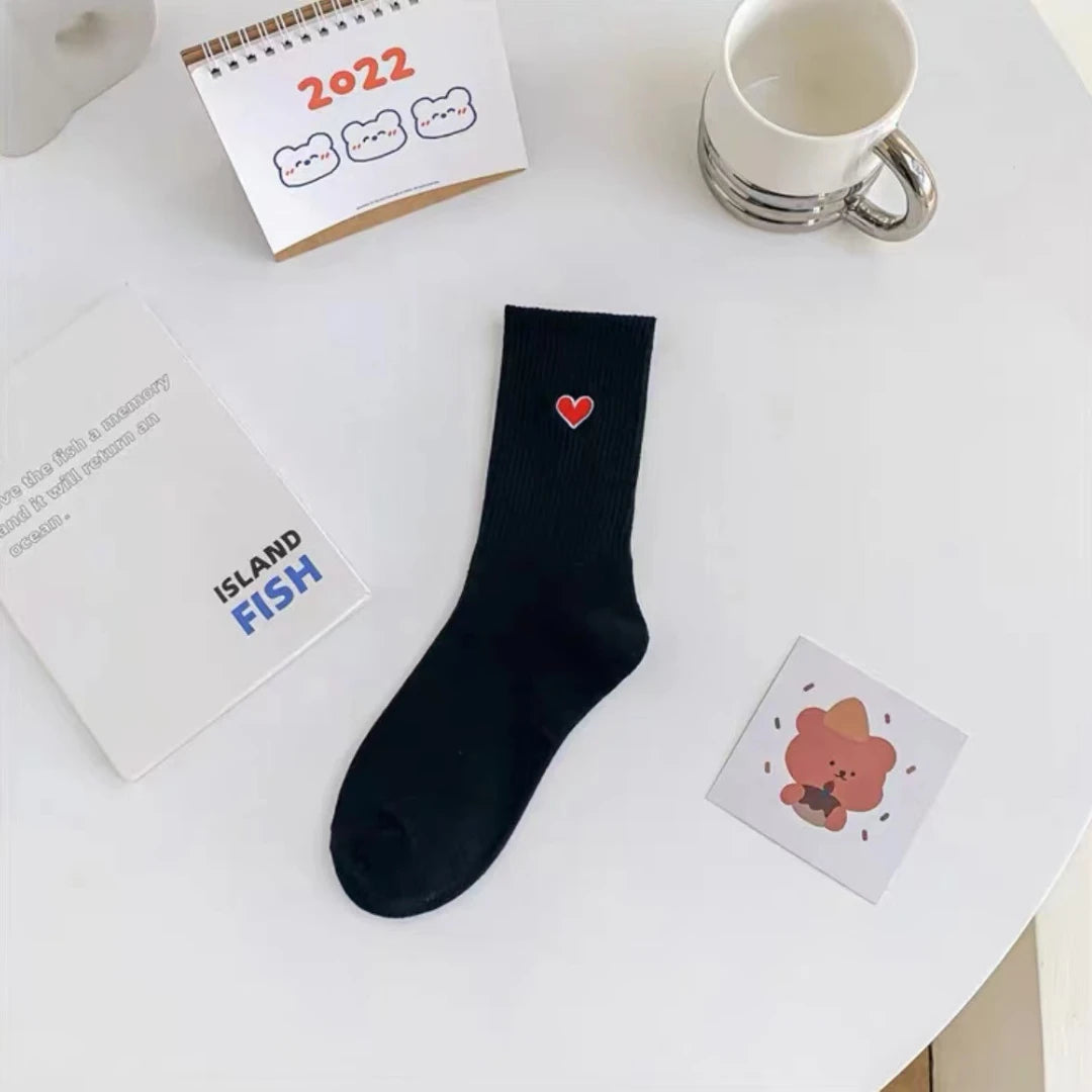 Josh & Tate - HeartStep™ Heart Crew Socks - Black sock with a red heart on a white surface with stationery items.