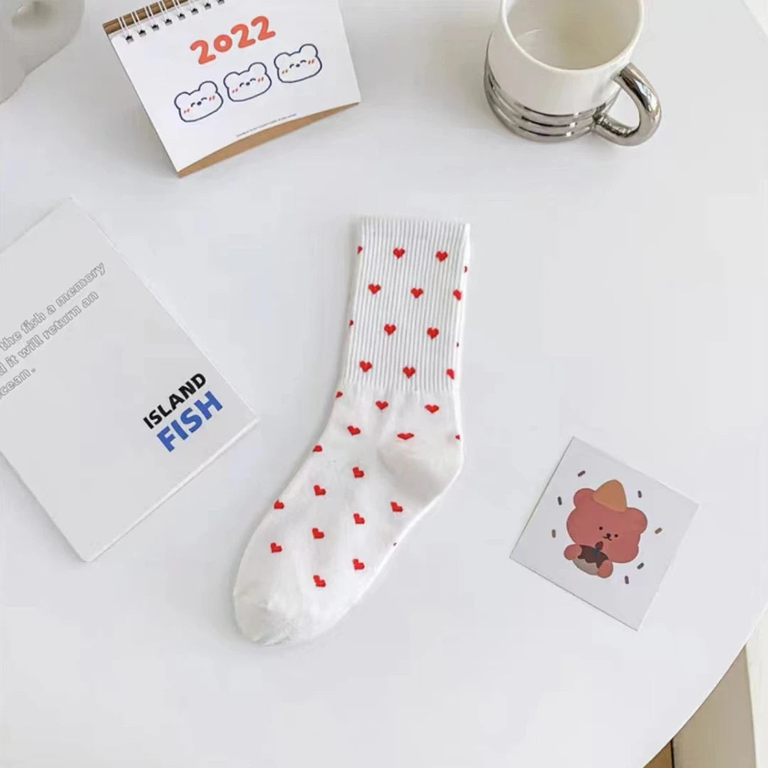 Josh & Tate - HeartStep™ Heart Crew Socks - White sock with red heart pattern on a white surface with stationery items.