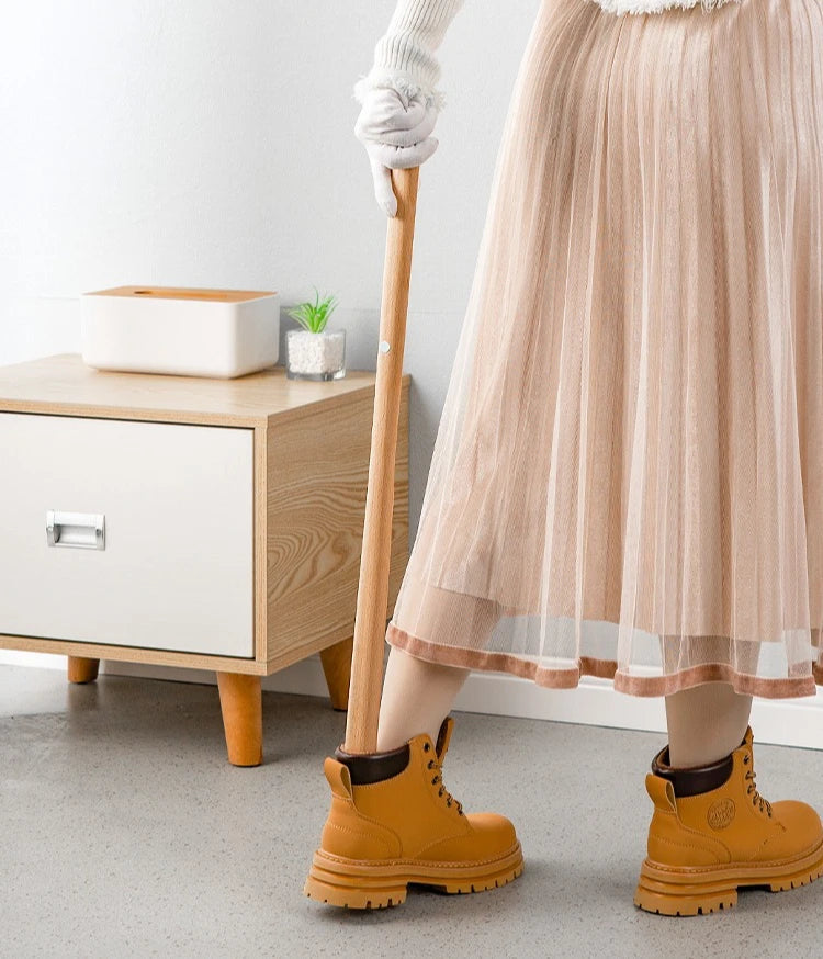 Person wearing yellow boots with a beige pleated skirt in a room.