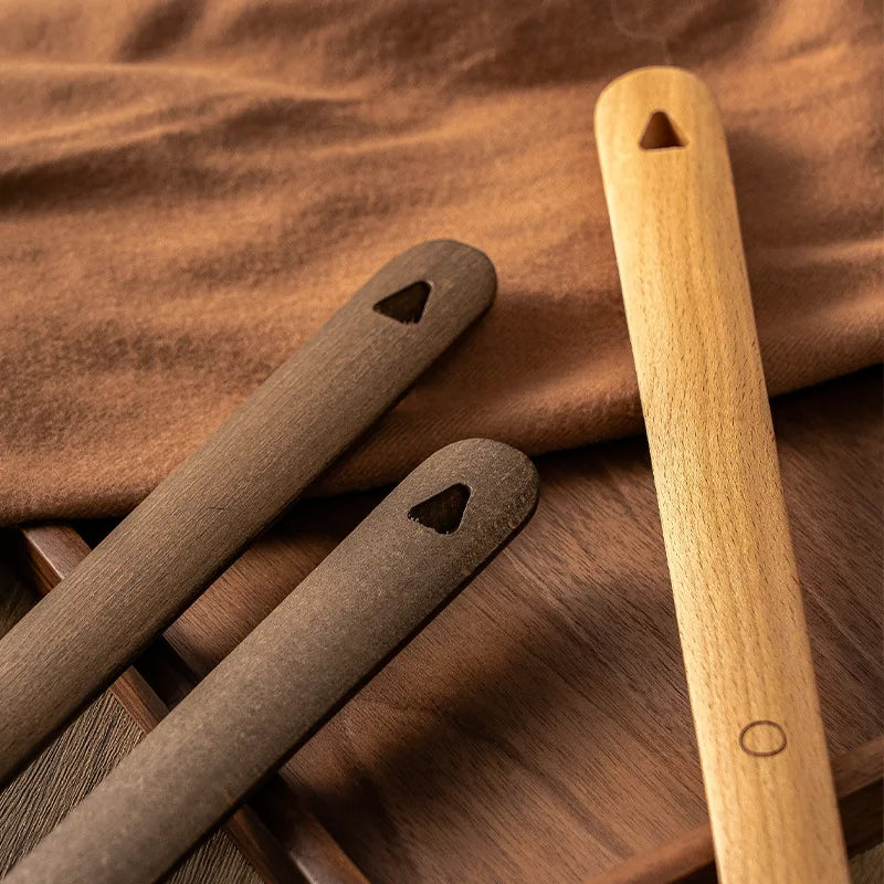 Three wooden tools with heart-shaped holes on a wooden surface