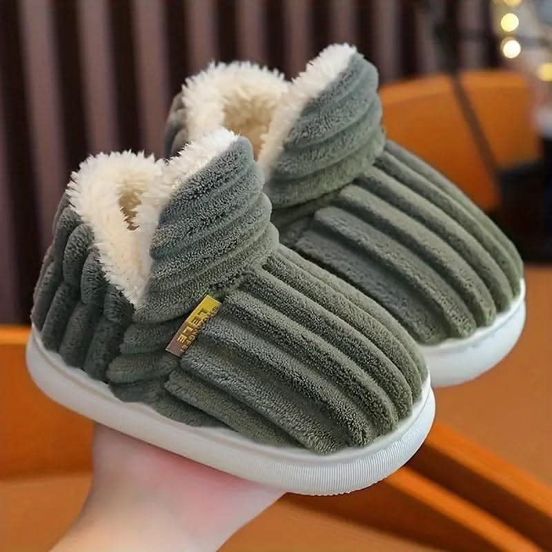 Green slippers with white fur lining held by a hand against a blurred background