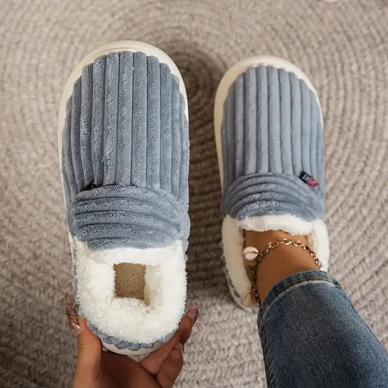 Blue slippers with white soles worn by a person on a textured surface