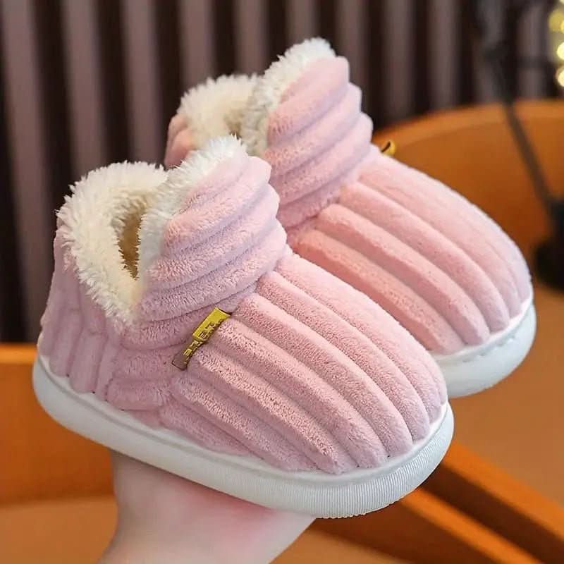 Pink plush slippers with a fluffy interior held by a hand against a blurred background
