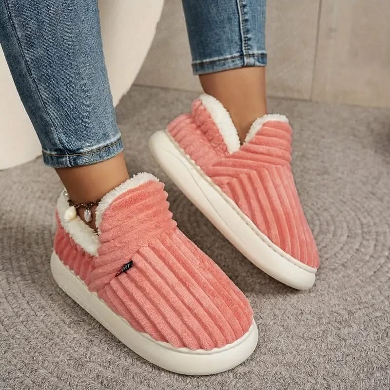 Pink slippers with white fur lining worn indoors on a carpeted floor.