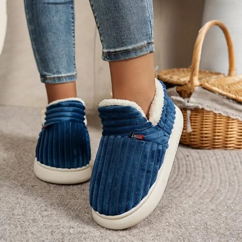 Blue slippers with white soles worn indoors on a carpeted floor.