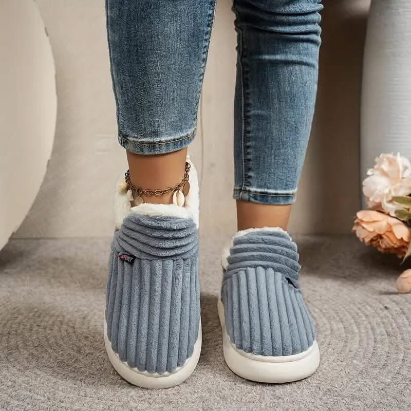 Blue slippers worn with jeans on a carpeted floor.