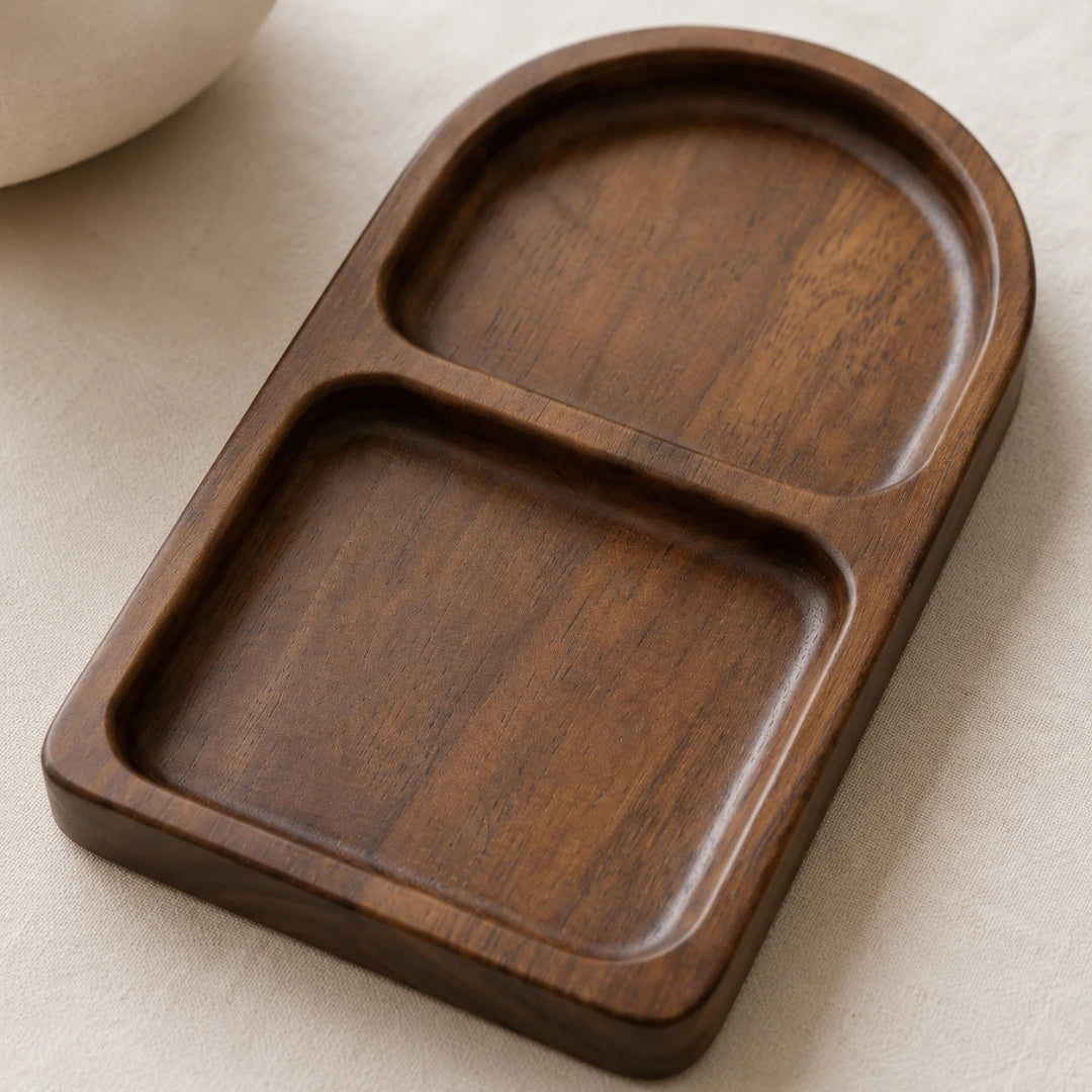 A dark brown wooden two-compartment tray with a smooth, rounded design, resting on a light beige textured fabric surface.
