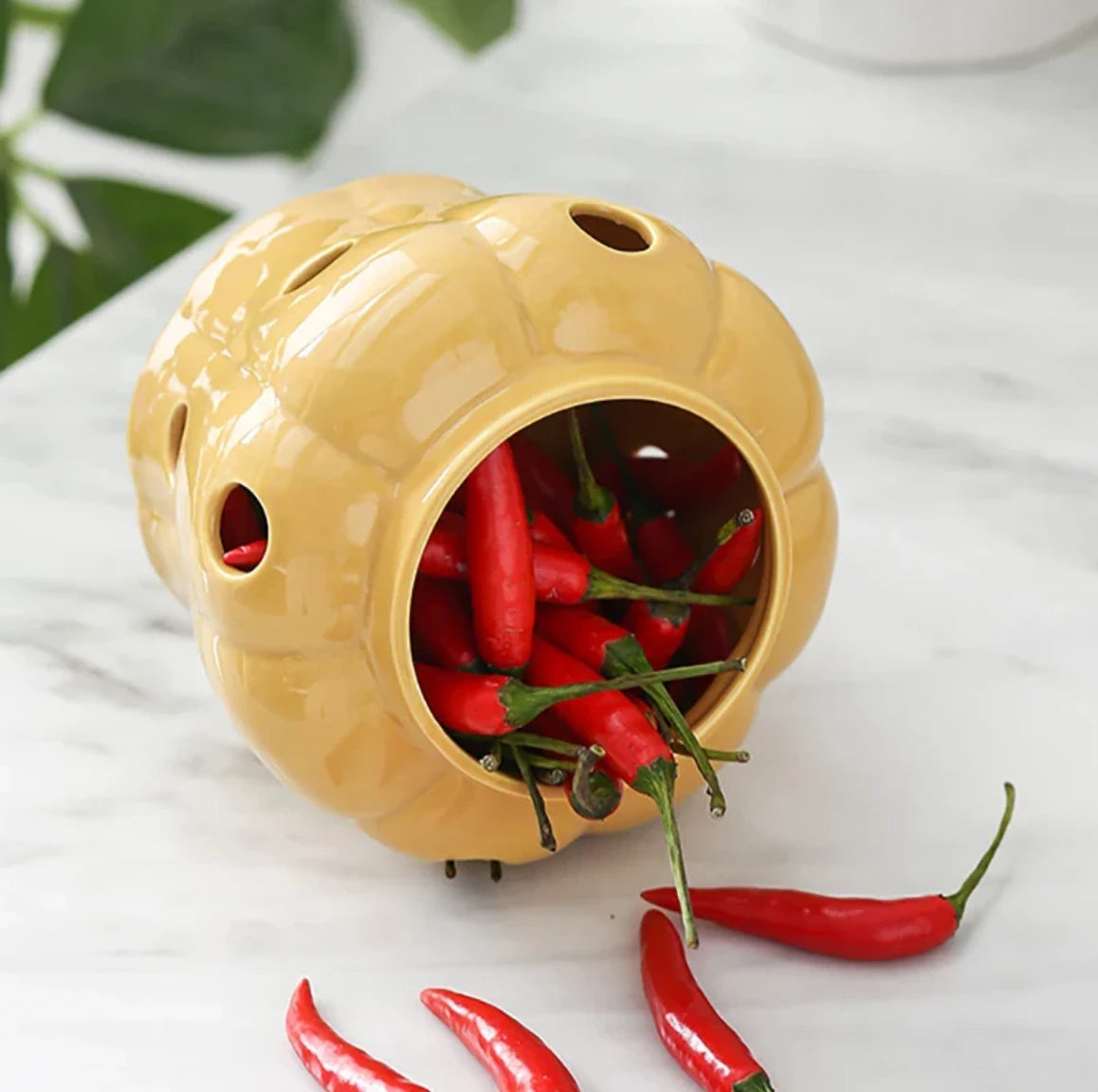 Yellow ceramic container with red chili peppers on a white surface