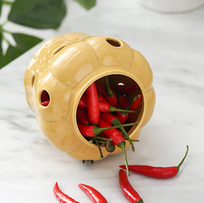 Yellow ceramic container with red chili peppers on a white surface