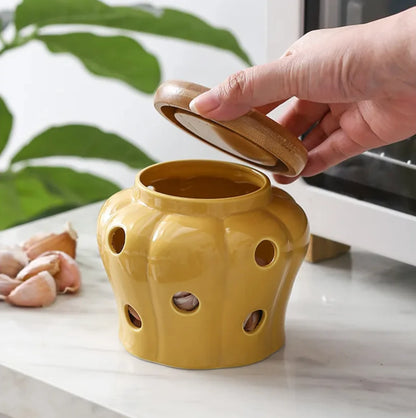Yellow ceramic container with holes on a white surface, hand holding a lid.