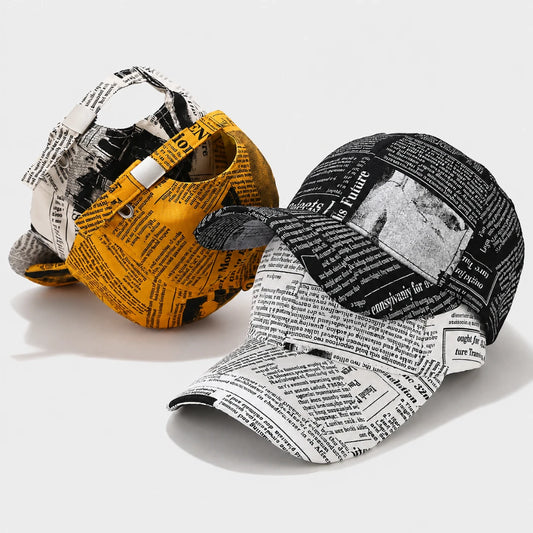 Josh & Tate - InkPress™ Newsprint Cap - Three baseball caps with a newspaper print pattern, shown in yellow, black, and white colorways on a light gray background.