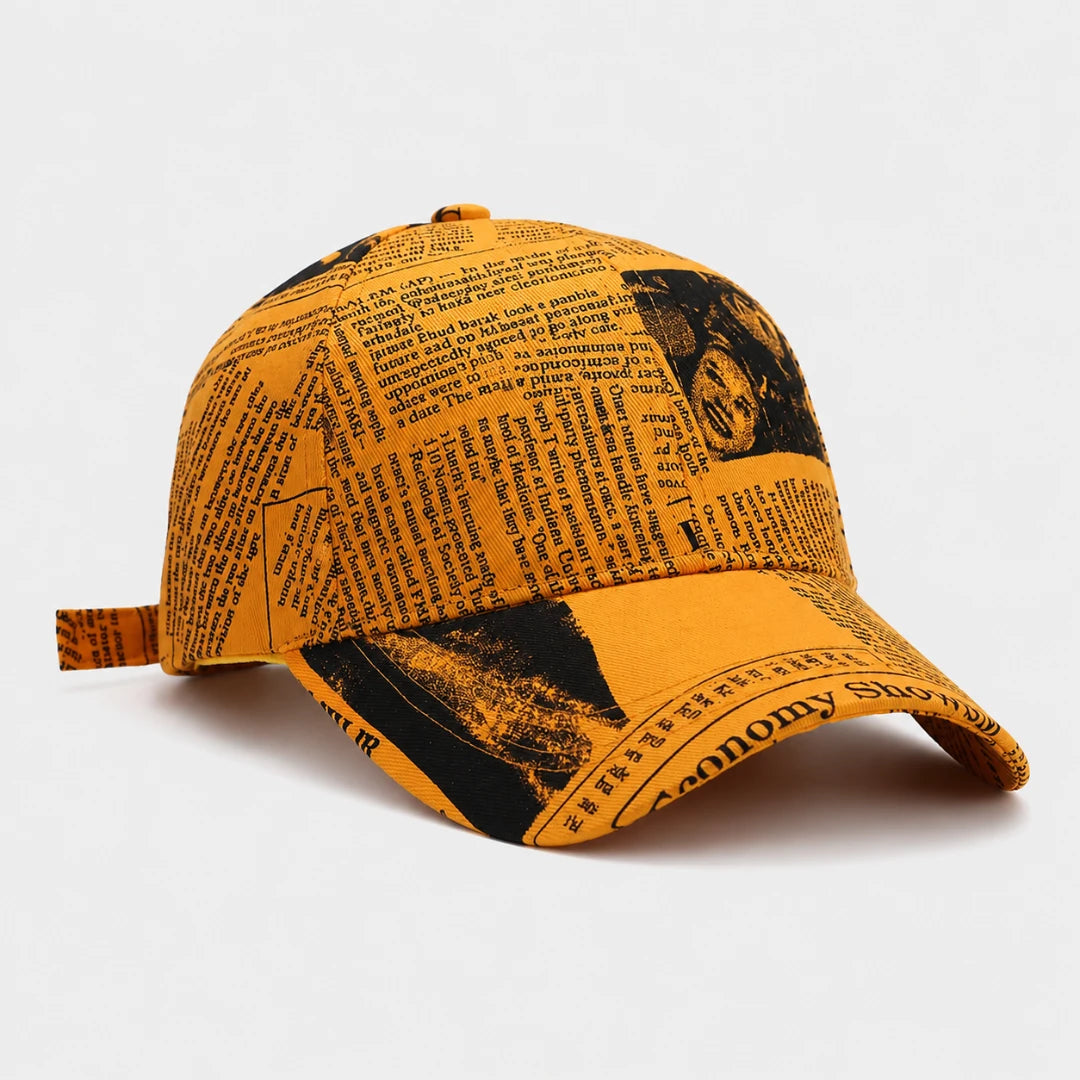 Josh & Tate - InkPress™ Newsprint Cap - A yellow baseball cap with a black newspaper print pattern, photographed on a clean white background.