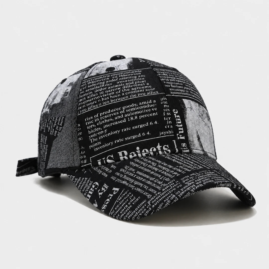Josh & Tate - InkPress™ Newsprint Cap - A black and white baseball cap featuring a newspaper print pattern with political and economic text, shown on a light gray background.