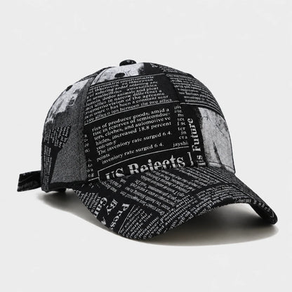 Josh & Tate - InkPress™ Newsprint Cap - A black and white baseball cap featuring a newspaper print pattern with political and economic text, shown on a light gray background.