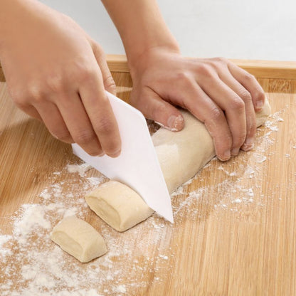 Hands cutting dough with a knife on a wooden surface