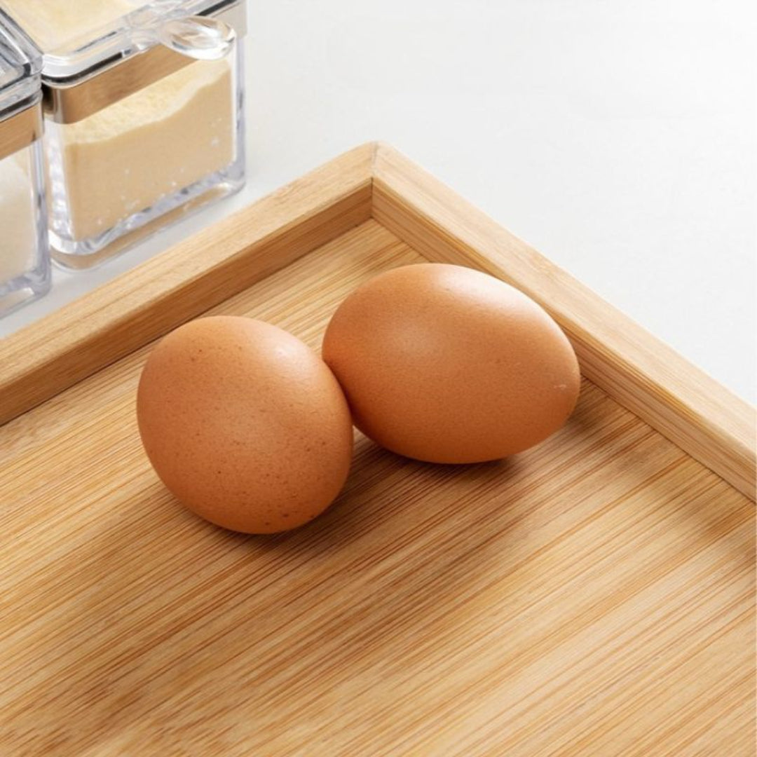 Two brown eggs on a wooden tray with a blurred background