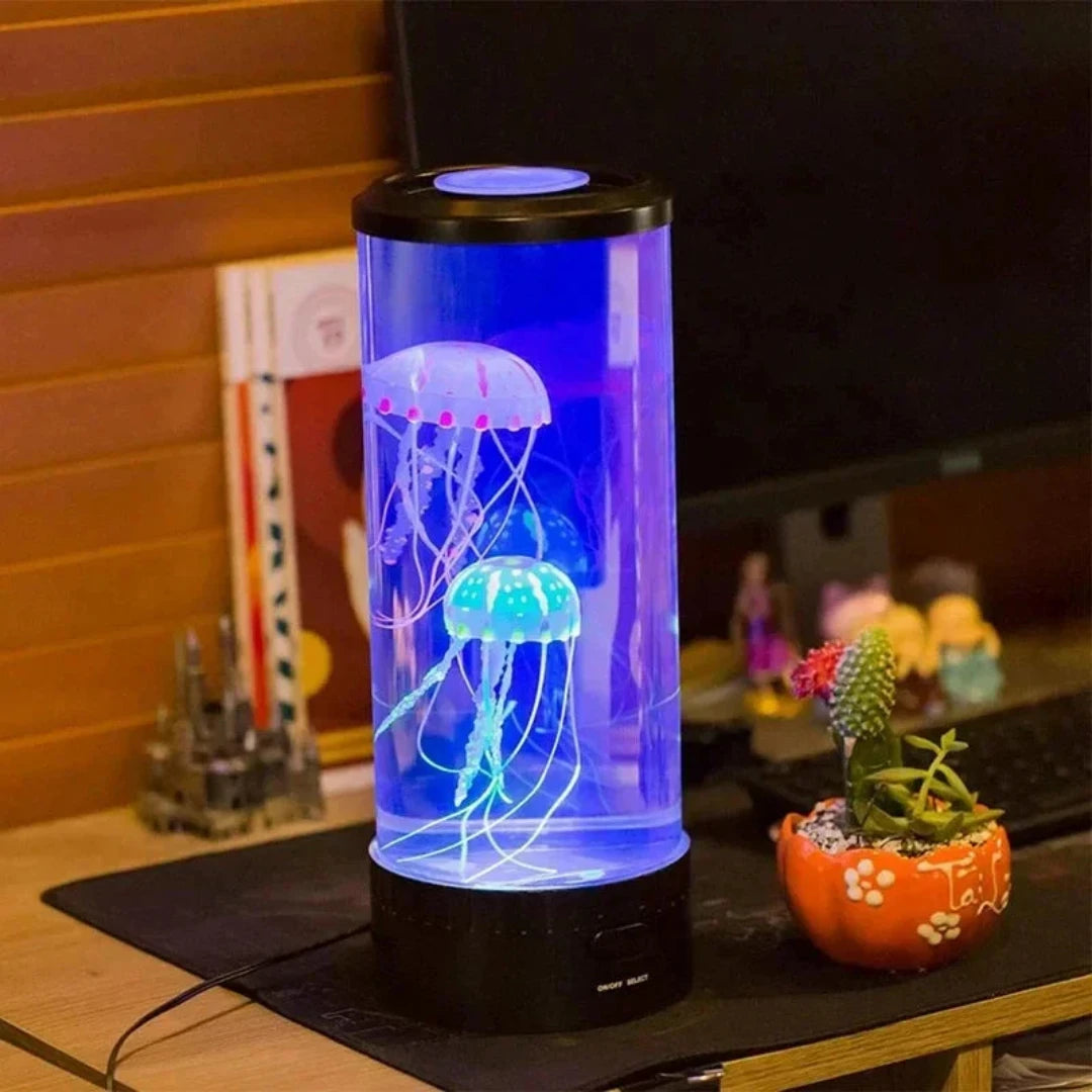 Josh & Tate - LED Jellyfish Ambient Night Lamp - Jellyfish-shaped lamp glowing in a cylindrical container on a desk.