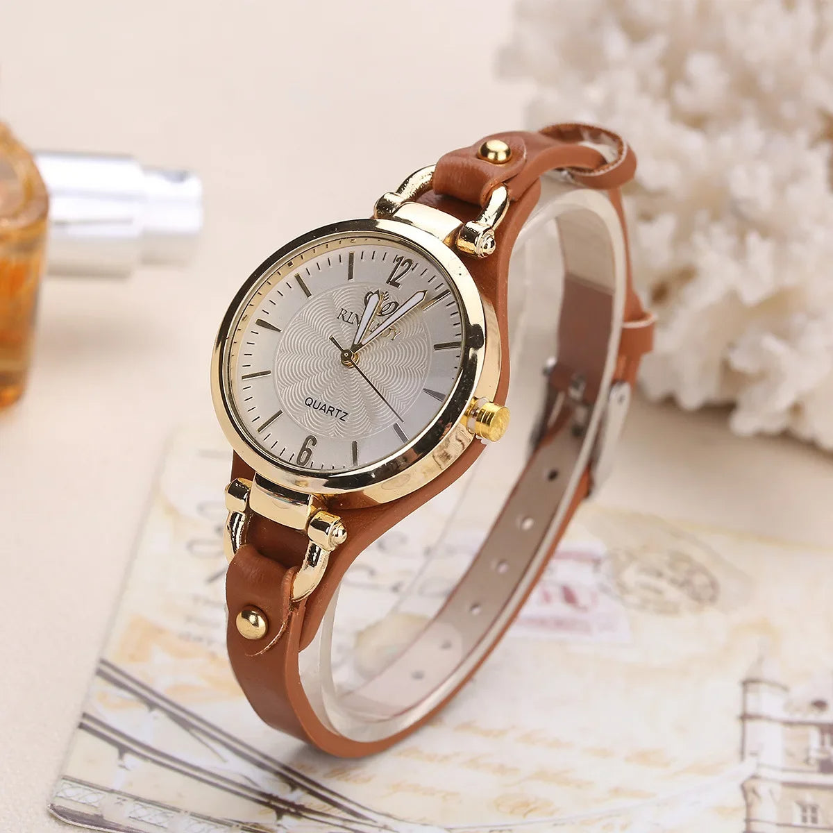Wristwatch with brown leather strap and gold casing on a surface with a blurred background
