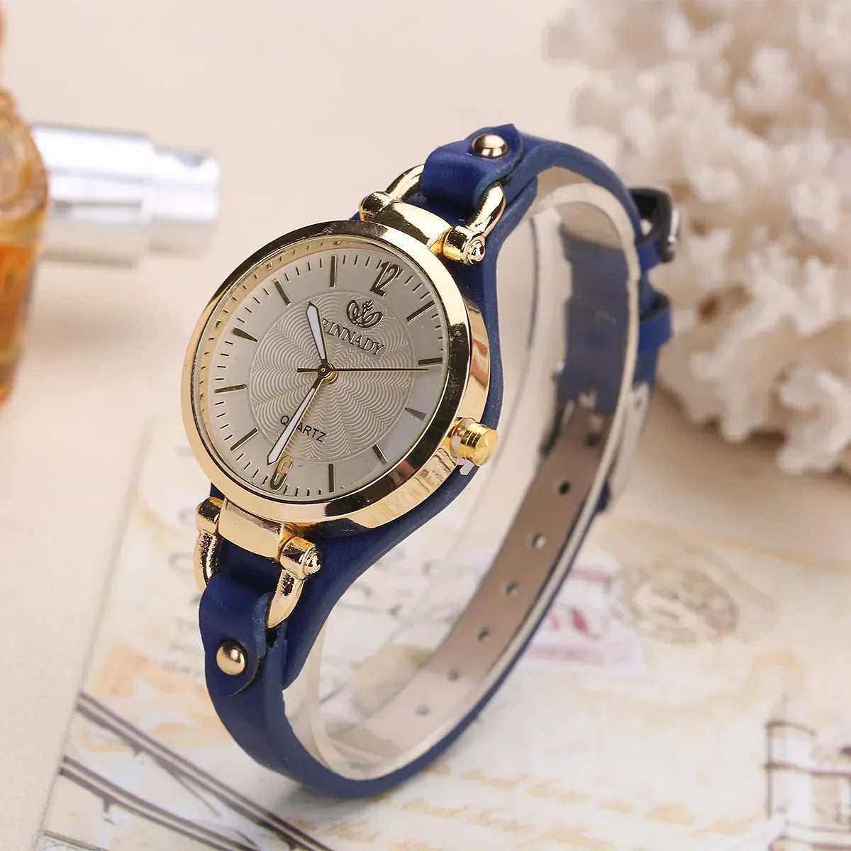 Wristwatch with blue strap and gold accents on a decorative background