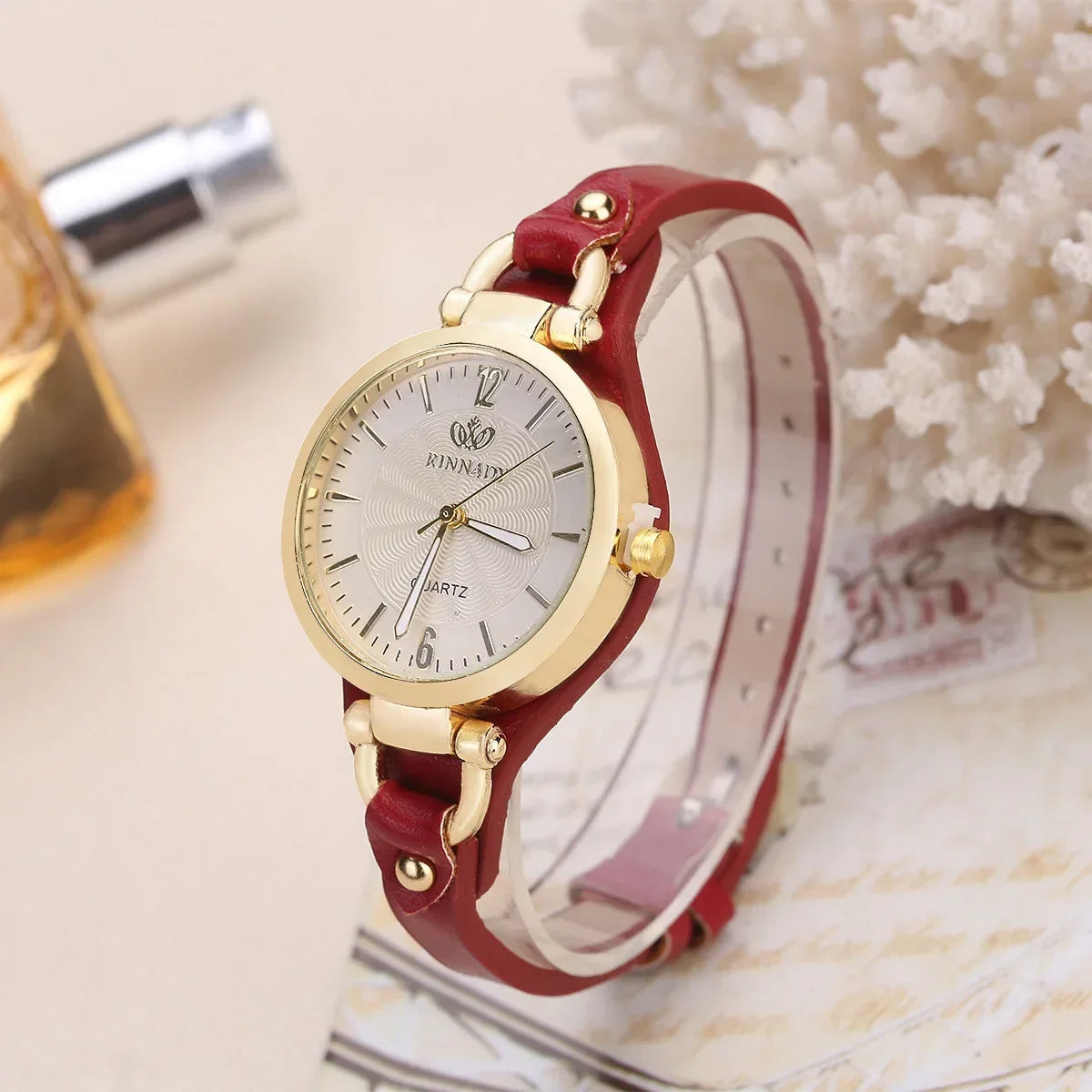 Wristwatch with red strap and gold casing on a light background