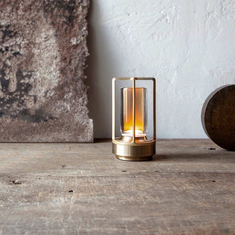 Small brass lantern with a warm glow on a wooden surface.