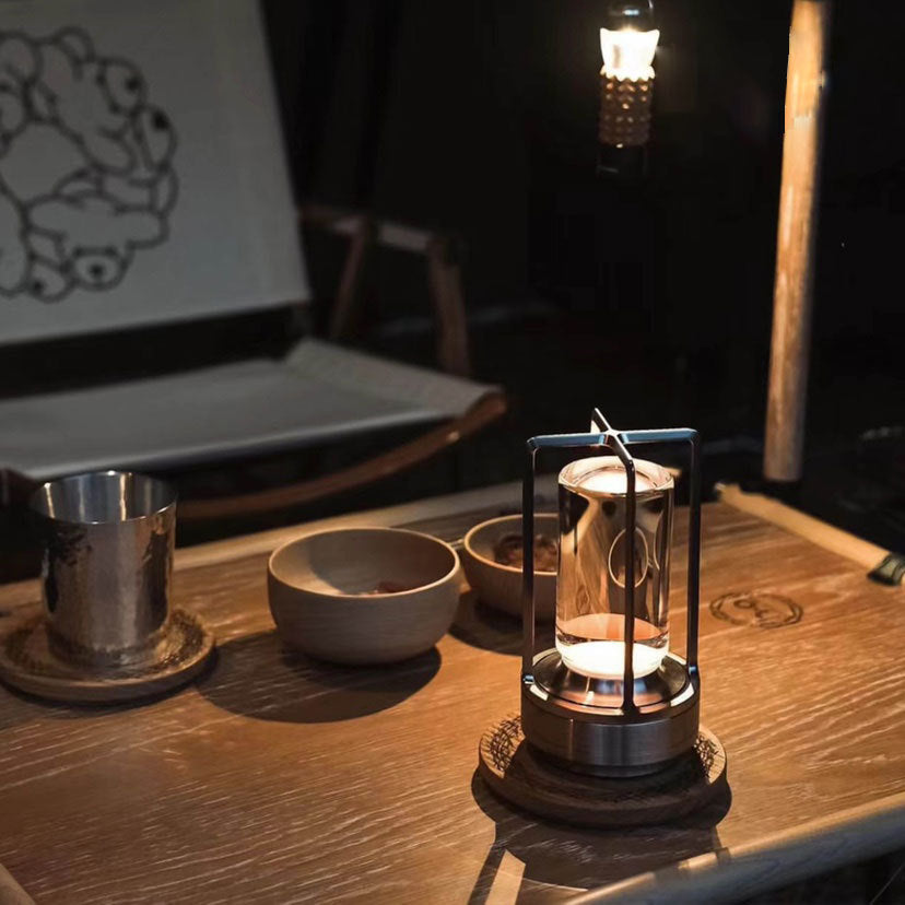 Candle lantern on a wooden table with a laptop in the background