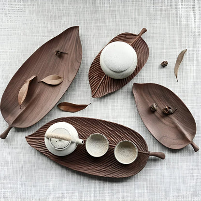 Josh & Tate - Leaf Shaped Wooden Serving Tray - Wooden leaf-shaped trays with ceramic items on a textured surface