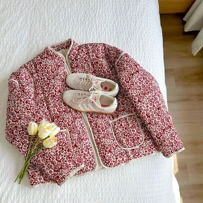 Floral-patterned jacket on a bed with white sneakers and yellow flowers.