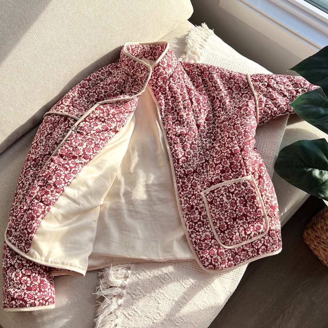 Floral-patterned jacket on a white surface with a plant in the background