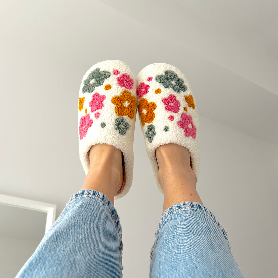 White slippers with floral patterns worn indoors against a neutral background