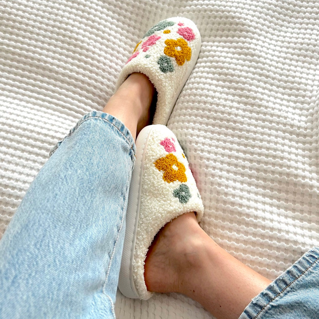 Floral slippers worn with light blue jeans on a textured surface