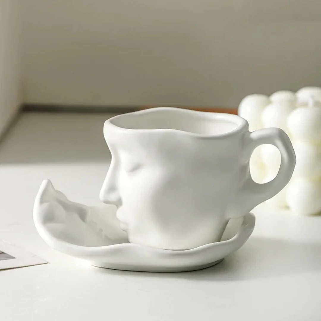 White ceramic face-shaped cup and saucer on a light surface