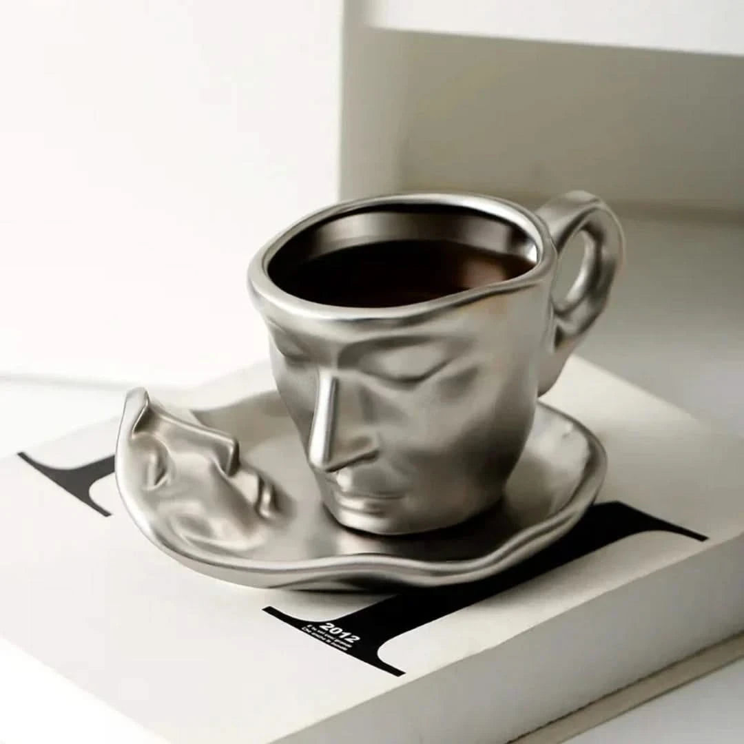 Josh & Tate - Lover's Gaze Reverie Coffee Ceramic Mug - Metallic face-shaped coffee cup and saucer on a magazine