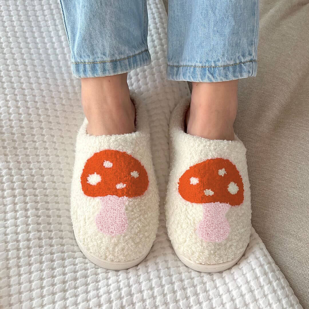 White slippers with mushroom design worn by a person on a textured surface