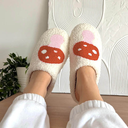 White fuzzy slippers with red mushroom design worn indoors.