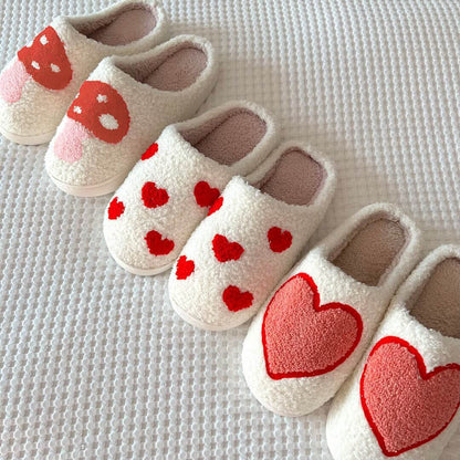 Pair of white slippers with red heart designs on a textured surface