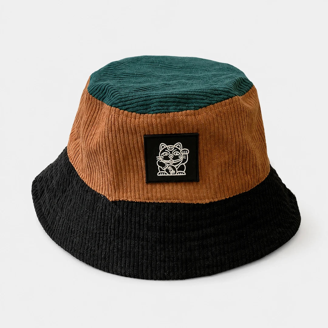 Josh & Tate - LuckyBrim™ Colorblock Bucket Hat - A three-tone corduroy bucket hat in dark teal, brown, and black, featuring a black square patch on the front with a white cartoon cat logo and the text 'KITTEN'.