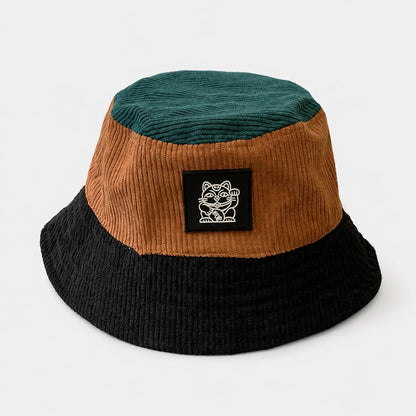 Josh & Tate - LuckyBrim™ Colorblock Bucket Hat - A three-tone corduroy bucket hat in dark teal, brown, and black, featuring a black square patch on the front with a white cartoon cat logo and the text 'KITTEN'.