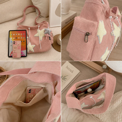 Josh & Tate - LuckyStar™ Ribbed Tote Bag  - A pink corduroy shoulder bag shown in a four-panel collage on a soft beige surface. The bag has cream star appliques, a small plush charm, a zipper pocket, and multiple open pockets.