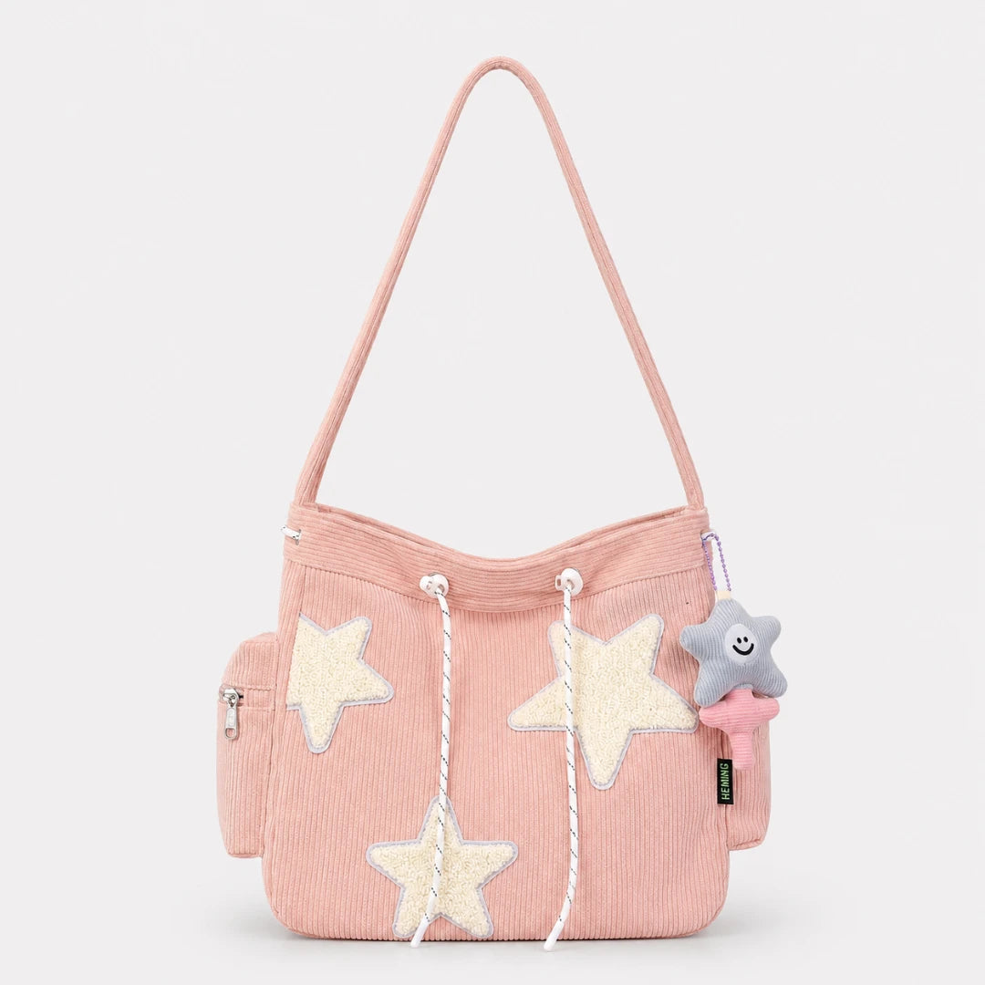 Josh & Tate - LuckyStar™ Ribbed Tote Bag  - A light pink corduroy shoulder bag with cream star appliqués, white rope drawstrings, and a small plush star charm, shown against a light gray studio background.