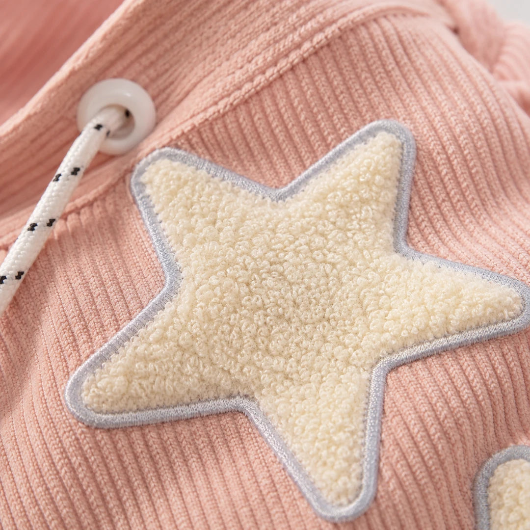 Josh & Tate - LuckyStar™ Ribbed Tote Bag - Close-up of a pink ribbed knit garment featuring a large cream fleece star applique with a gray stitched border and a white drawstring cord.