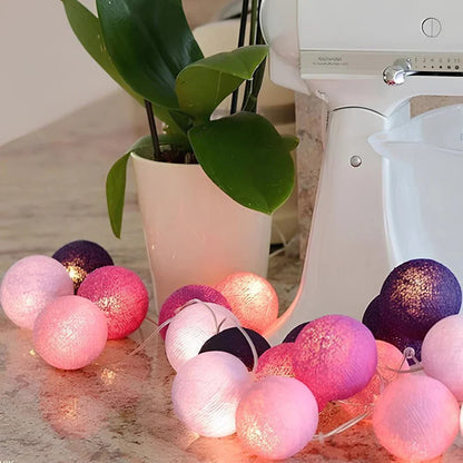String of colorful cotton ball lights on a kitchen counter with a plant and mixer in the background.