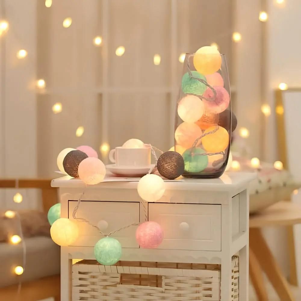 Decorative string lights with colorful balls on a small table in a softly lit room.