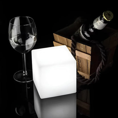 Glowing cube light next to a wine glass and bottle on a dark background