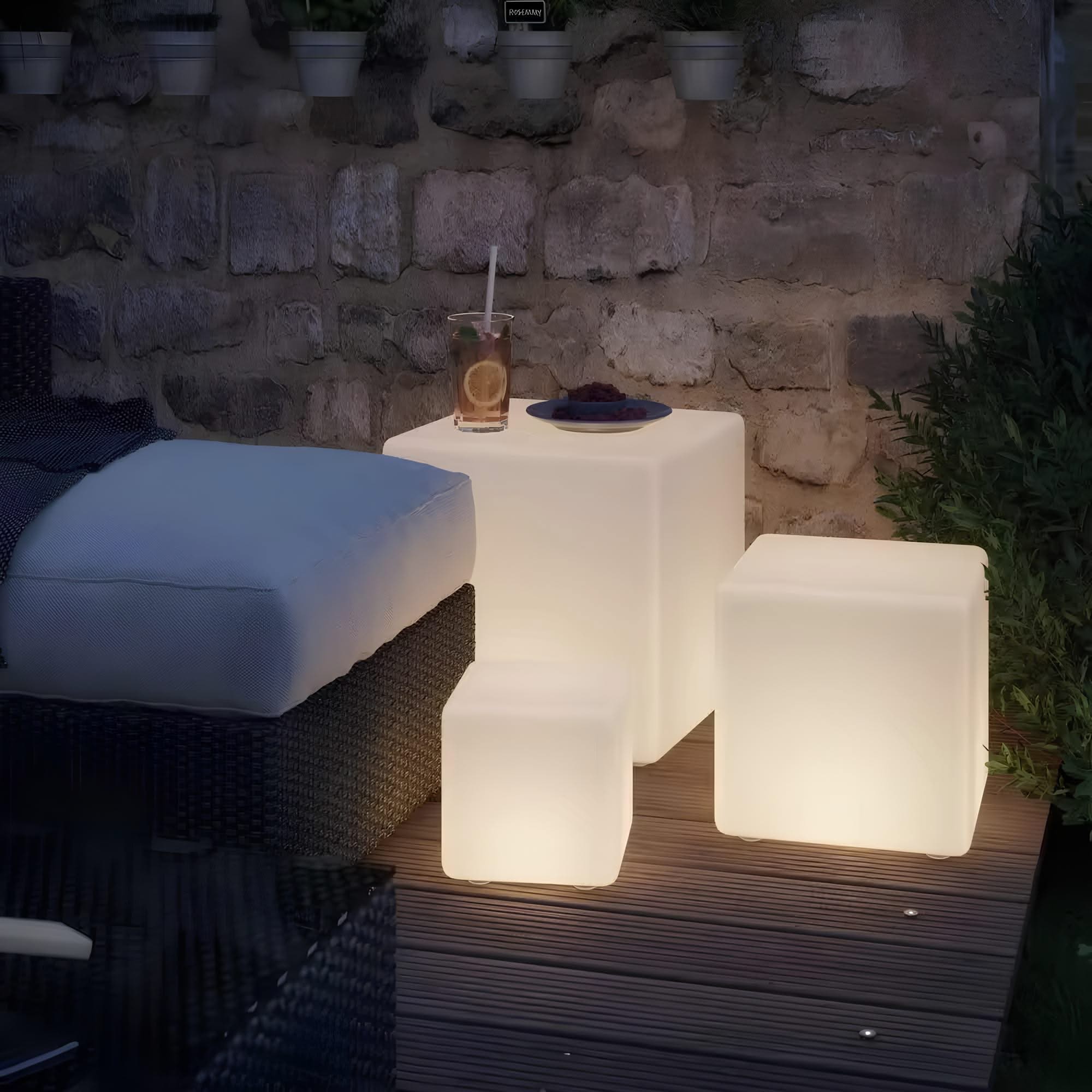 Outdoor setting with illuminated cube-shaped lamps against a stone wall.